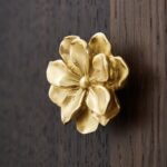 Gold magnolia flower cabinet knob on white drawer