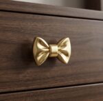 Solid brass drawer handle shaped like a bow with polished gold finish