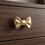 Solid brass drawer handle shaped like a bow with polished gold finish