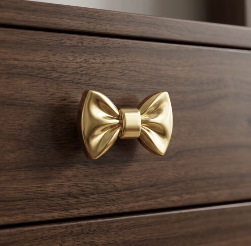 Solid brass drawer handle shaped like a bow with polished gold finish