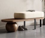 Walnut bench with sculptural sphere base, black steel legs and cream bouclé cushion in a modern entryway