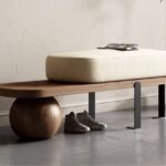 Walnut bench with sculptural sphere base, black steel legs and cream bouclé cushion in a modern entryway
